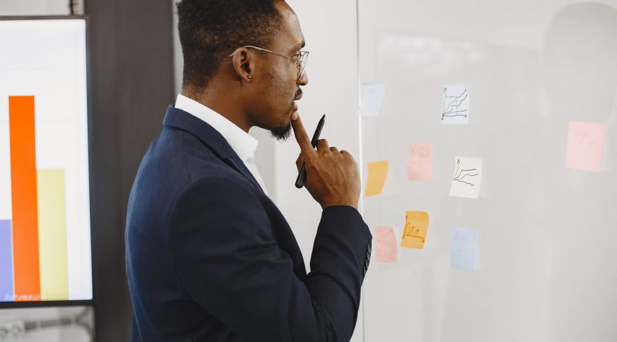 African man in a black suit. Man writing on the glass.
